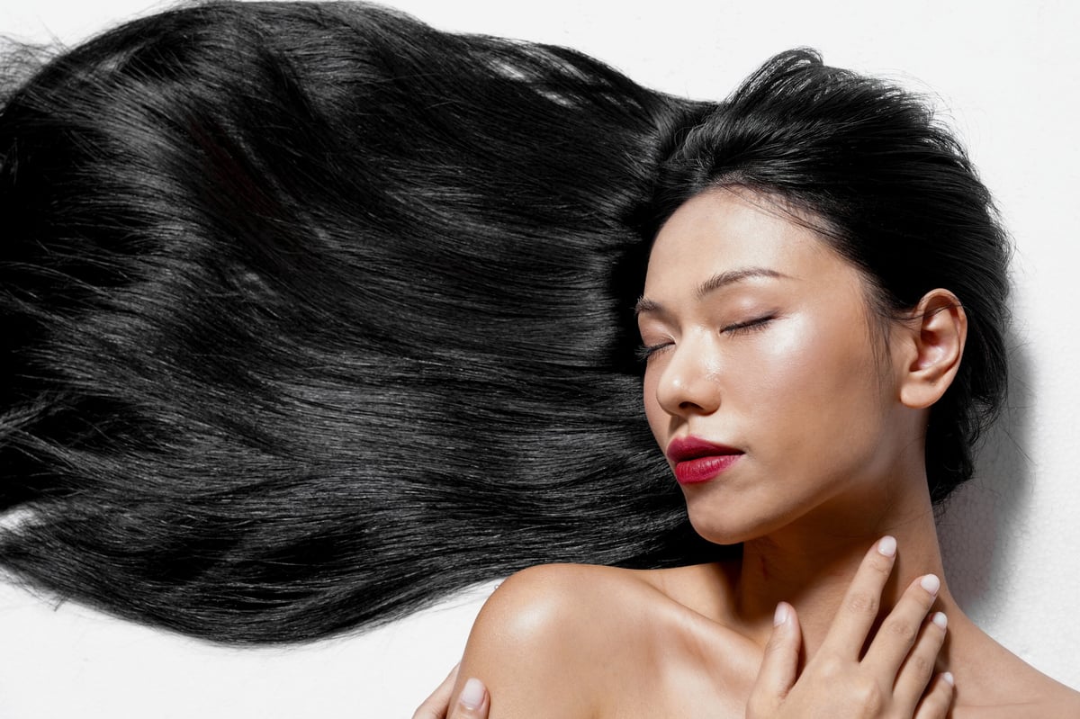 Beautiful woman with healthy shiny long hair demonstrating proper hair care routine